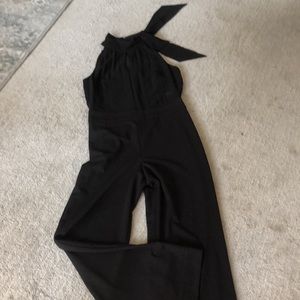 Black jump suit. Sleeveless. High neck with neck tie. Hidden back zip closure.